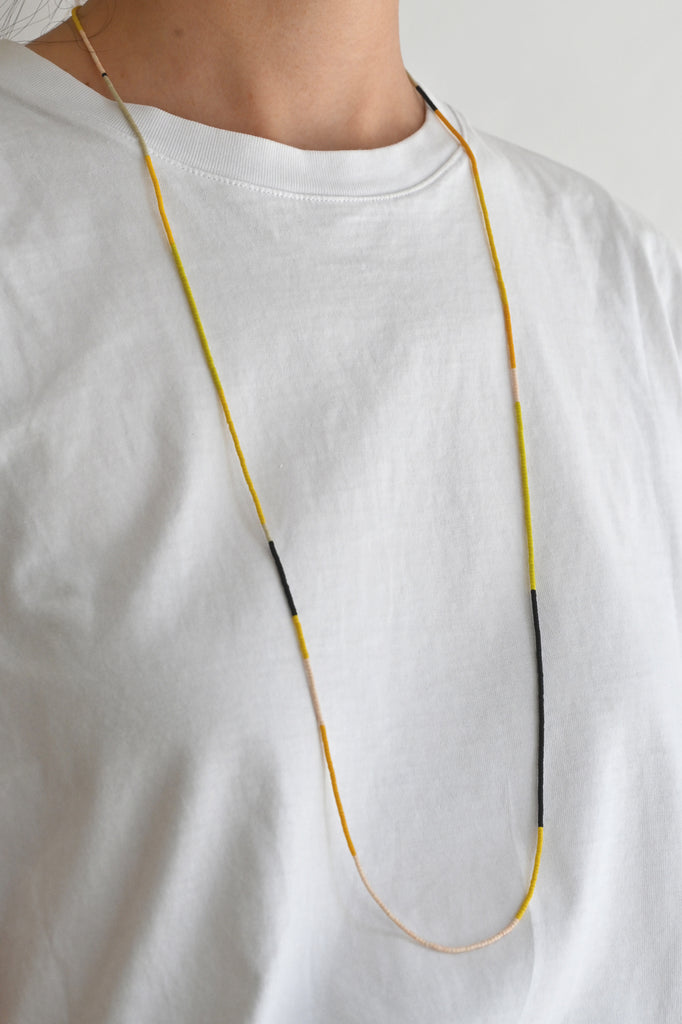 A Yellow Sun Wrap styled as necklace at Abacus Row Handmade Jewelry